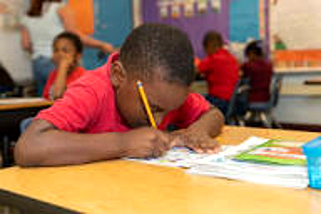 A Beacon student writing at his desk