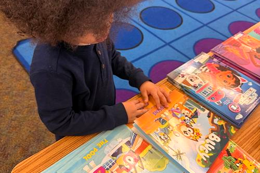 A young Beacon student choosing a book at the Scholastic book fair
