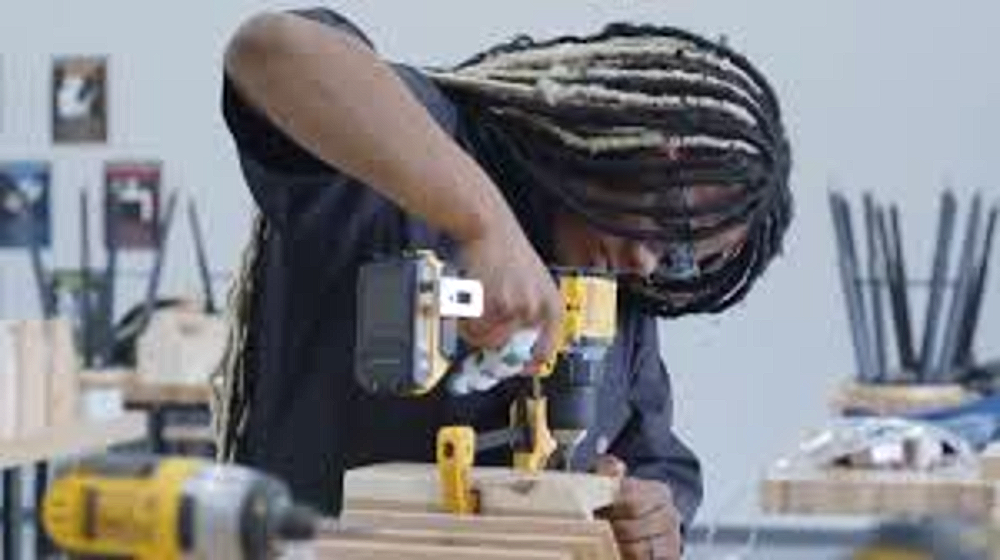 A Harper Woods CCI student using a power drill in the construction trades shop