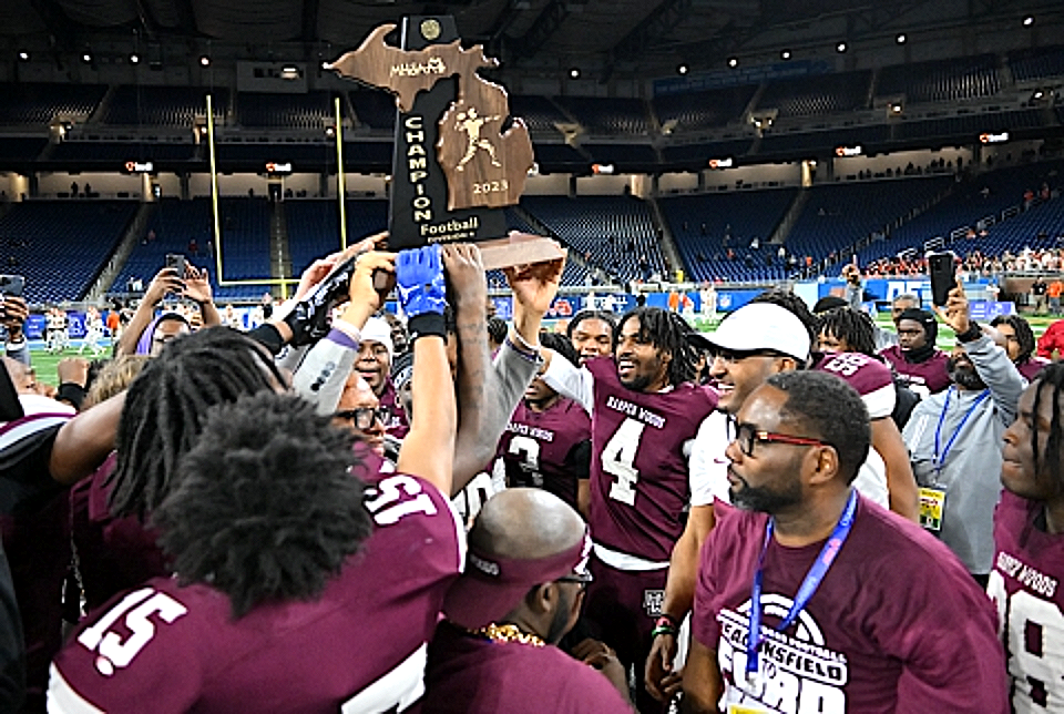 Harper Woods players lifting the MHSAA Division 4 state championship trophy at Ford Field