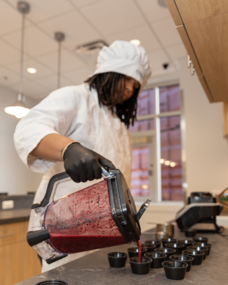 A culinary student pouring fresh smoothie servings