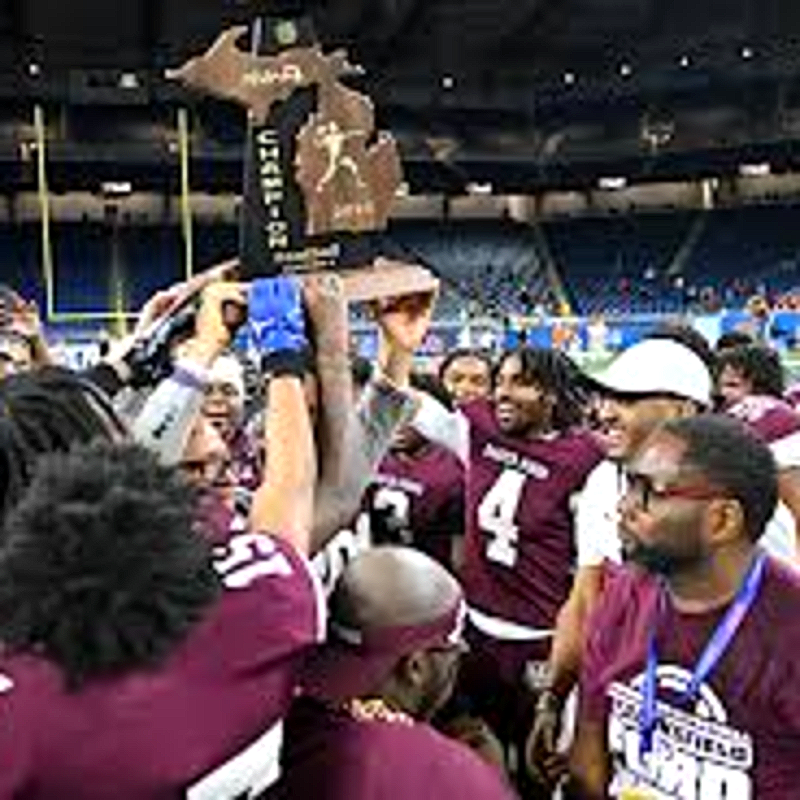 Harper Woods Hornets football players lift the championship trophy at Ford Field