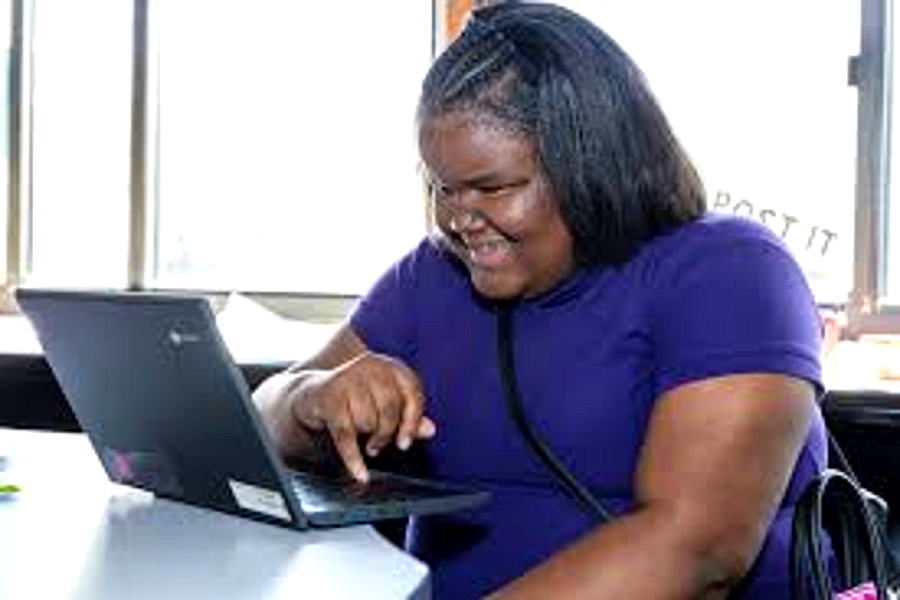 A Harper Woods Middle School student smiling at his laptop