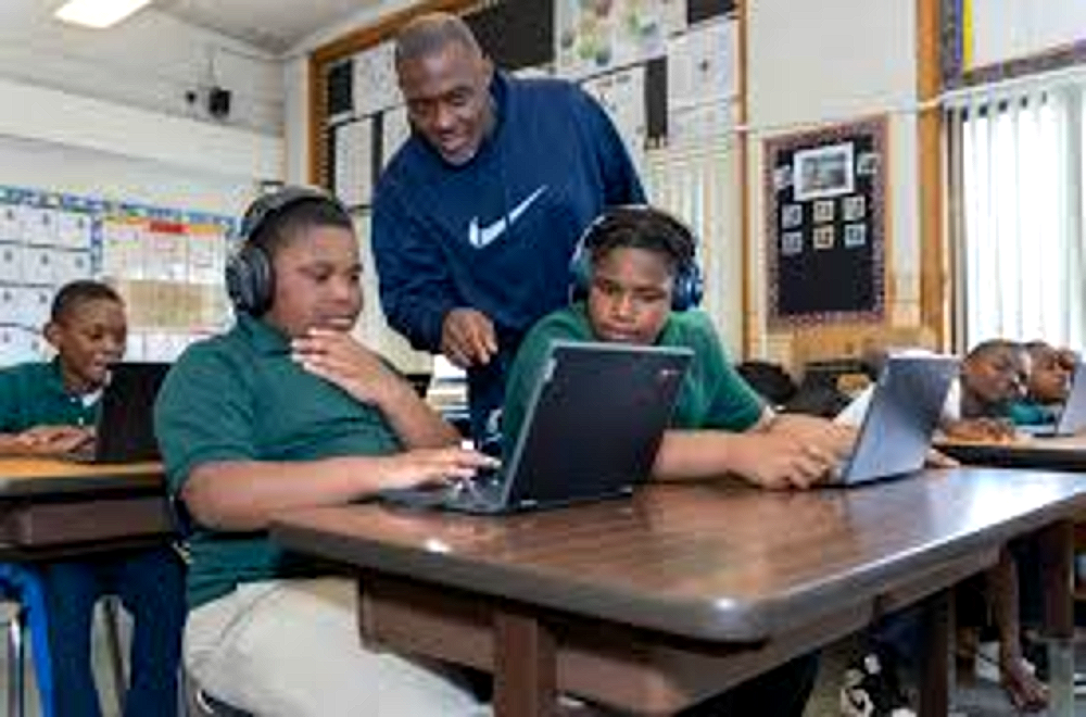 Tyrone students working with laptops and headphones alongside a teacher